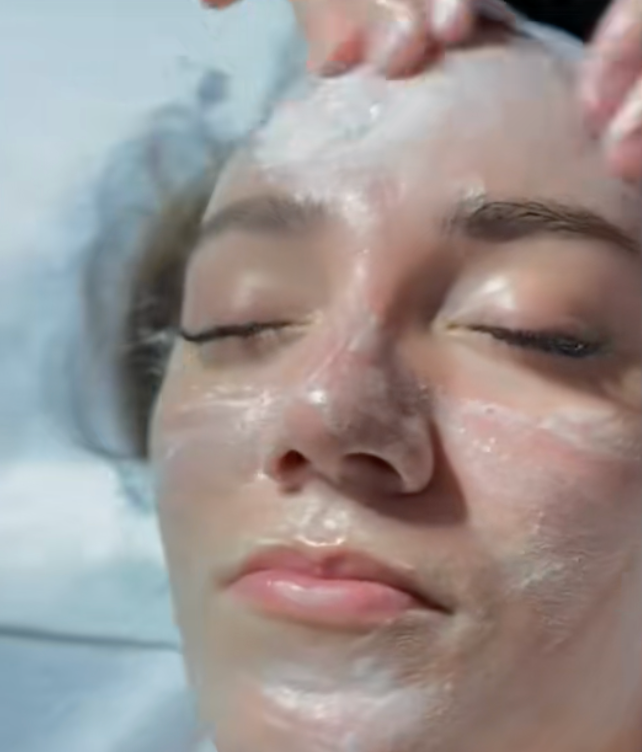 Skincare specialist applying a facial cleansing treatment to a client
